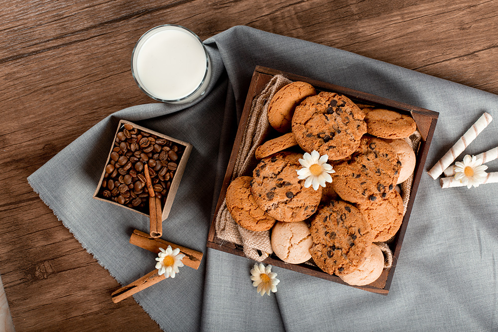 a wooden box filled with cookies next to a glass of milk
