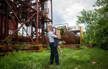 a man holding a woman on his back in front of a factory