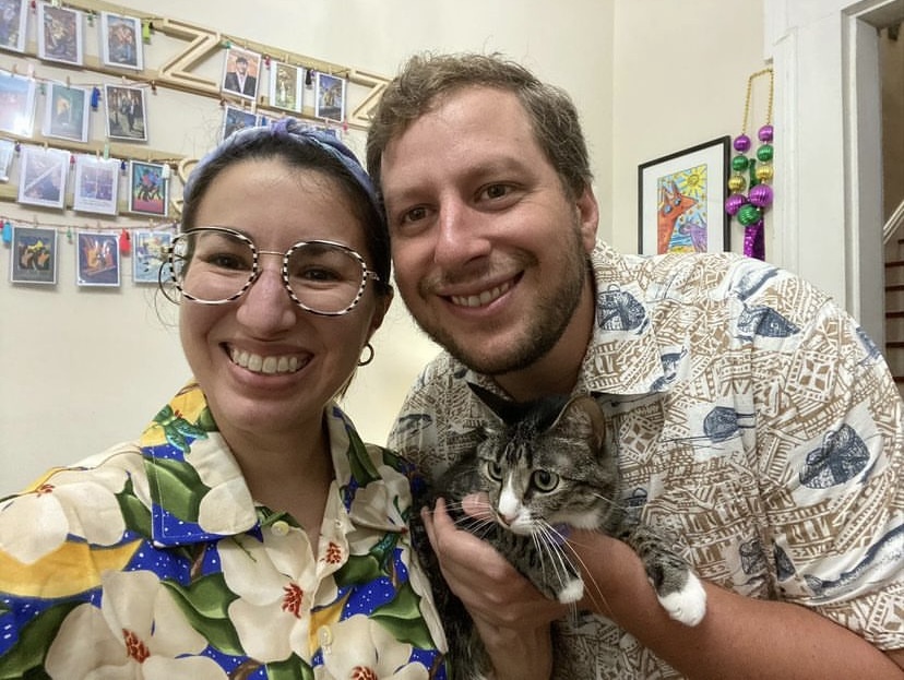 a man and woman pose for a picture with a cat
