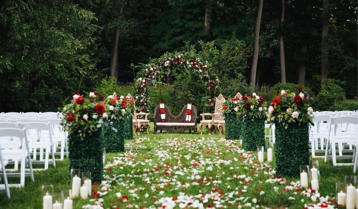 an outdoor ceremony with white chairs and red flowers